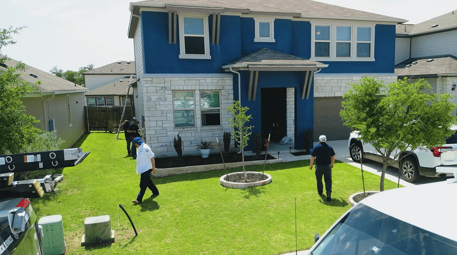 Blue home in Liberty Hill, Texas neighborhood with electricians onsite for repairs after a direct lightning strike.