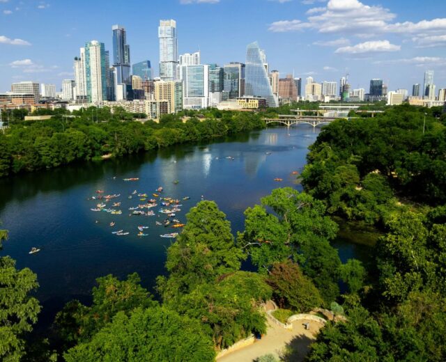 Aerial view of kayakers in Lady Bird Lake with the Austin skyline in the background