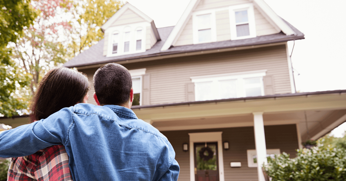 A couple standing in front of their new home.