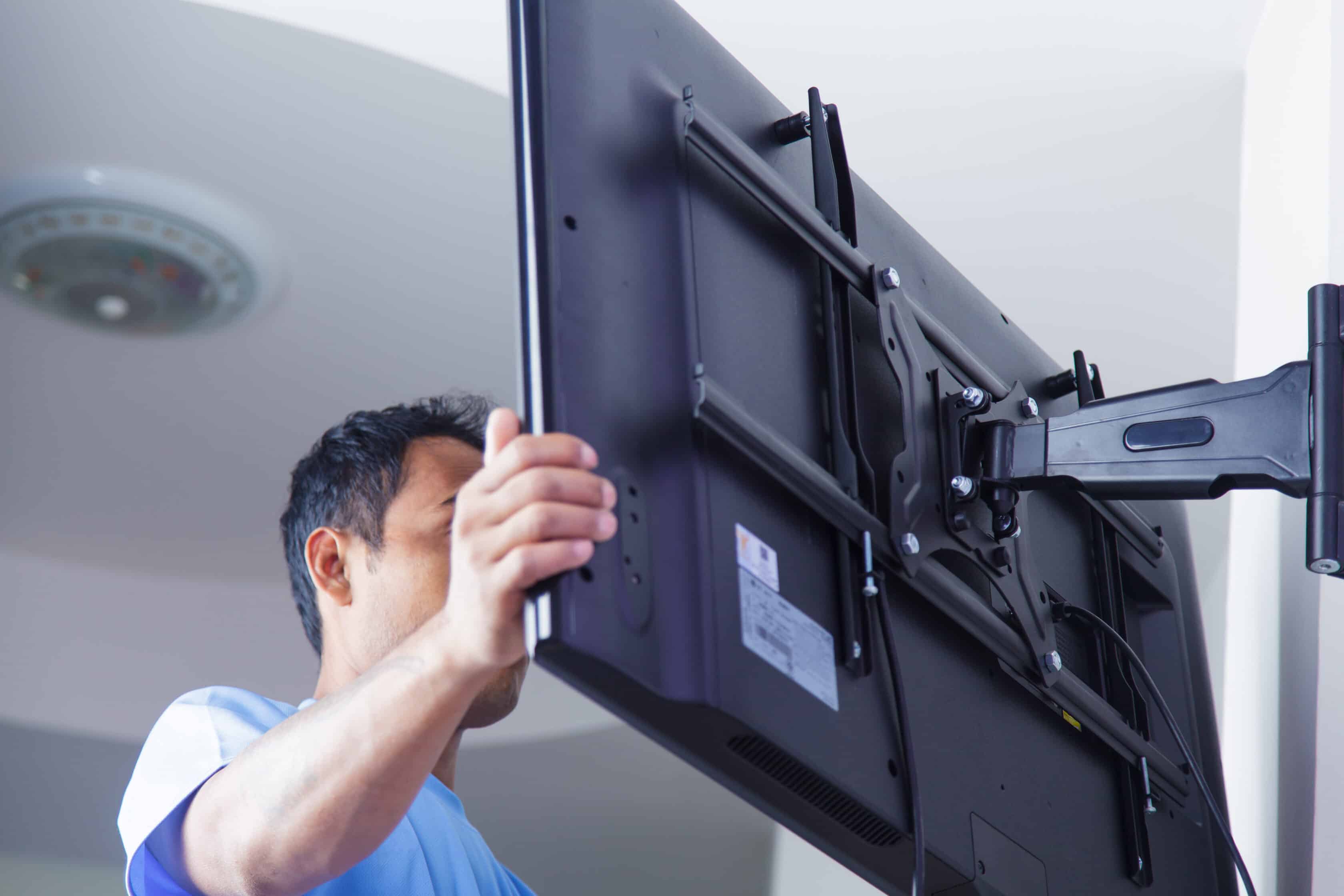 Technician mounting a TV in a home.
