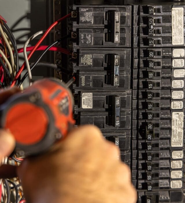 Electrician installing an electrical circuit breaker in a power panel