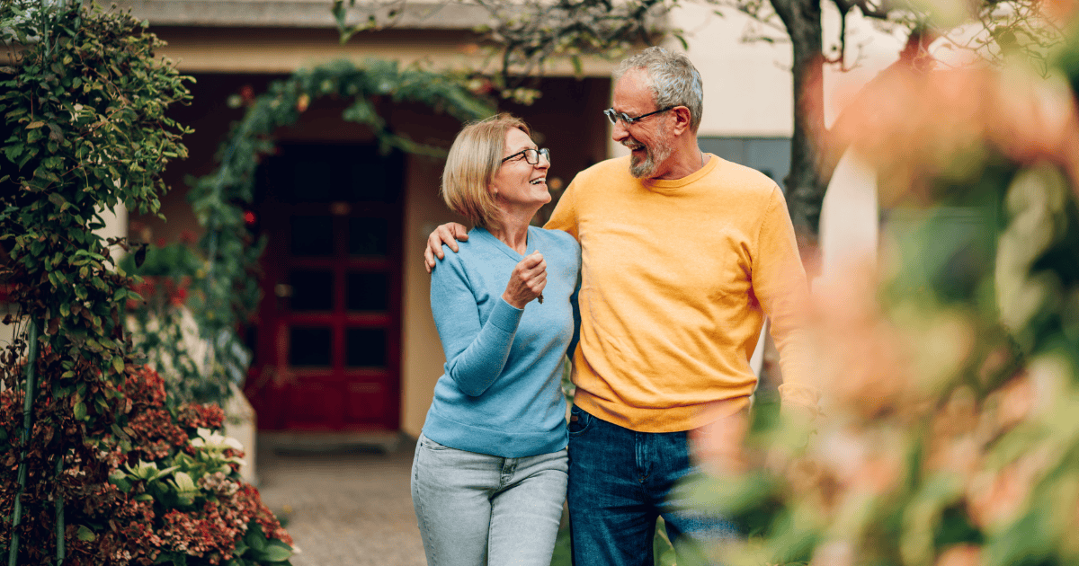 A couple embracing in front of their home.