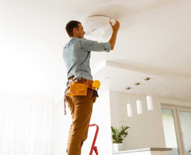 Technician installing a new light fixture in a residential home.
